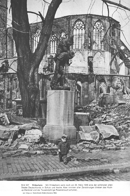 Das Huckup-Denkmal von Hildesheim steht
                        nach dem Feuersturm vom 22. M�rz 1945 intakt
                        mitten in Ruinen, im Hintergrund die Ruine der
                        Andreaskirche