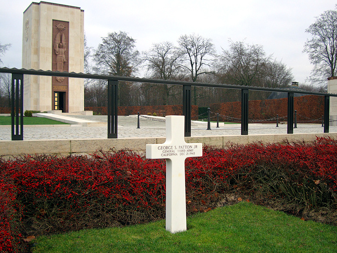 L�pida sepulcral de la tumba del
                            general Patton en Luxemburgo con el nidal
                            rojo con bayas rojas