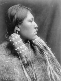 Nuu-chah-nulth-Frau mit
                                      Nasenring und in
                                      Holzfaserkleidern, Profil, ca.
                                      1910