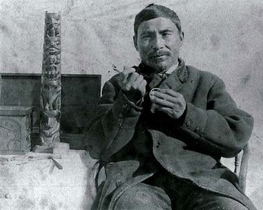 Charles
                  Edenshaw mit einem kleinen Totempfahl und mit
                  Schnitzwerkzeugen in der Hand