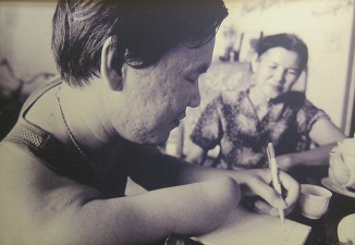 Agent-Orange-Opfer, Mutter Nguyen Thi Nguon mit Sohn: Le Dinh Thao 823) und seine Mutter Nguyen Thi Nguon arbeiteten im Krieg als Krankenschwester auf Schlachtfeldern von Ta Keo und Dong Thap. Nun arbeitet sie als Wanderverk�uferin, kauft und verkauft Flaschen, die sie in K�rben sammelt, die von ihrem Schulterstock herunterh�ngen. Diese Arbeit ist f�r sie notwendig, um ihren geistig behinderten Sohn zu versorgen, der durch Agent Orange verseucht wurde. Die geistige Behinderung ist derart schlimm, dass er den ganzen Tag �ber nichts mehr kann als unzusammenh�ngend herumzuschreien.