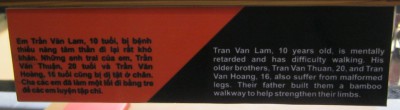Agent-Orange-Opfer Tran-Van-Lam, Text: Tran Van Lam (10) ist geistig zur�ckgeblieben und kann kaum laufen. Seine �lteren Br�der, Tran Van Thuan (20) und Tran Van Hoang (16) leiden ebenfalls unter deformierten Beinen. Ihr Vater hat ihnen einen Bambusweg, um ihre Glieder zu st�rken.