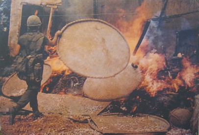 My-Lai-Massaker: Ein NATO-Soldat legt die Reisf�cher ins Feuer: Ein Soldat f�chert das Feuer mit den K�rben an, die zum Reistrocknen und Wurzeltrocknen verwendet werden.