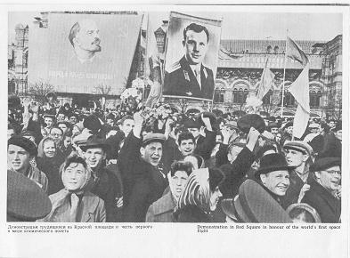 Gagarin-Faltprospekt (13), Feier
                                auf dem Roten Platz mit Plakaten von
                                Fallschirmspringer Gagarin neben dem
                                Kommunisten und Massenmrder Lenin
