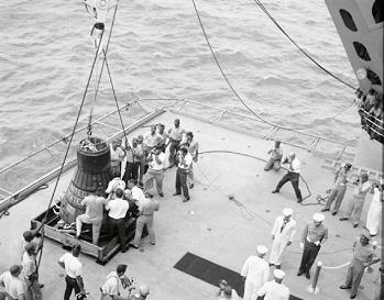 Cooper and the landing capsule on
                            board, photographers, foto no. S63-07854.