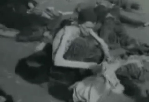 Ein deutscher Kriegsgefangener oben ohne
              durchsucht Kleider am Boden 01